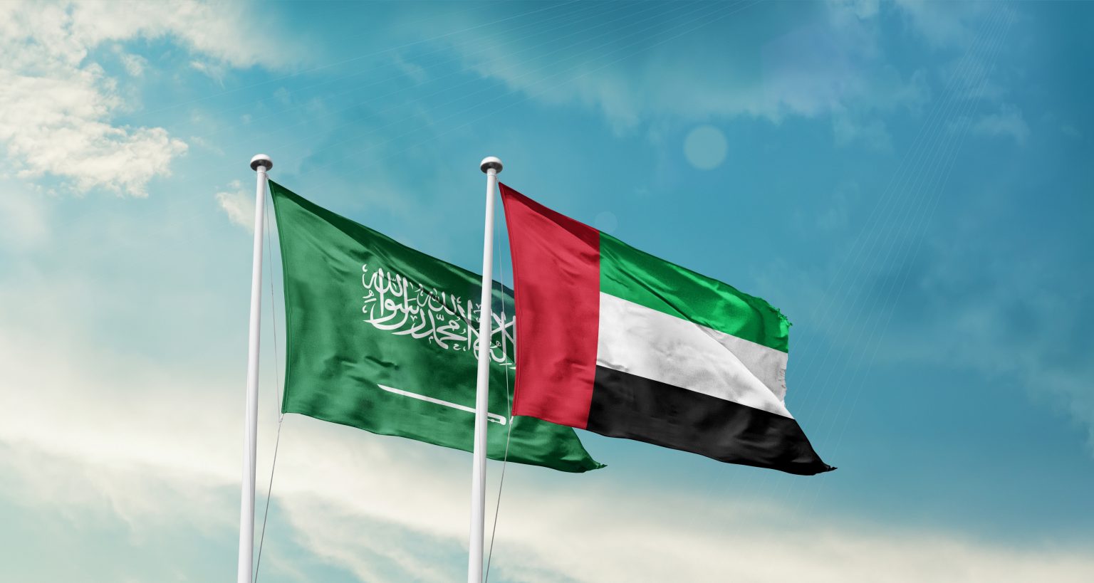 Saudi Arabia and UAE friendship flags are waving in the sky. Double country Flag waving with mast. Saudi Arabian UAE national flag for agreement / Shutterstock