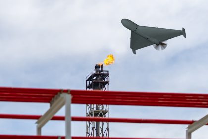 A military drone flies over an oil refinery