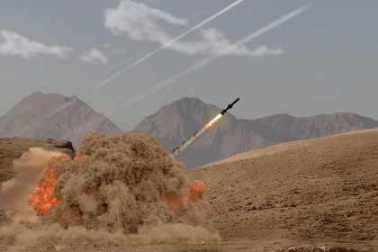 The rocket soars into the sky, leaving behind a trail of smoke in the desert in the middle of the mountains/Anelo/Shutterstock