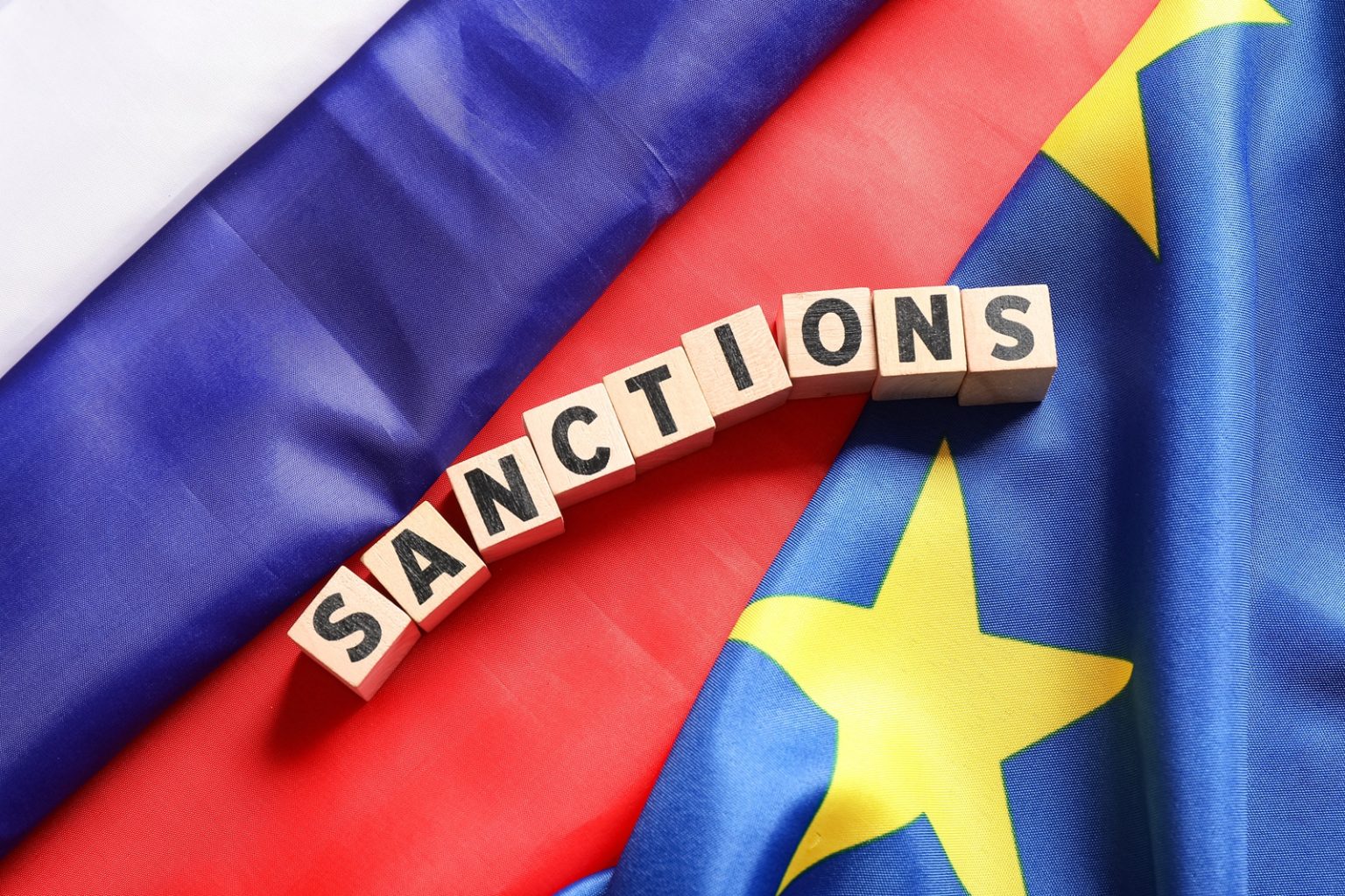 Word SANCTIONS on flags of Russia and EU, top view